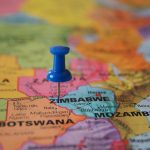 A blue pushpin marks Zimbabwe on a colorful close-up map highlighting its geographical position.