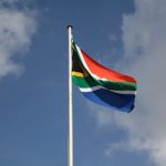 Vibrant South African flag waving proudly against a blue sky with clouds.